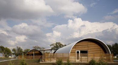 Two S-Model Quonset huts with custom wood end walls and white-bordered doors