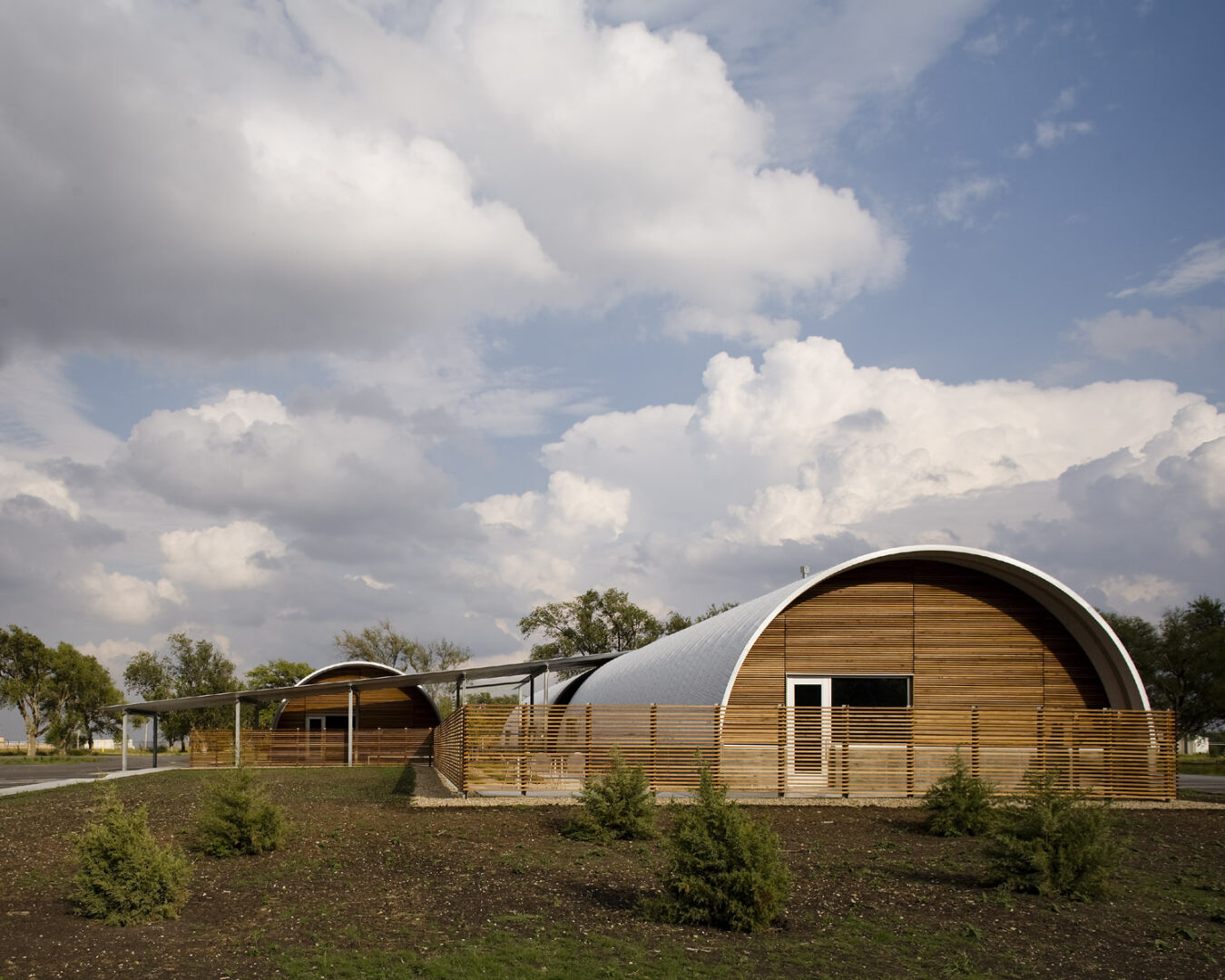 Two S-Model Quonset huts with custom wood end walls and white-bordered doors