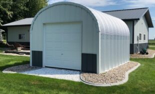 steel S model storage shed with custom white and grey front endwall and landscaping around the building and house behind it