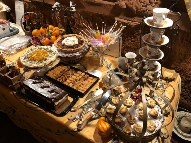 Table with an array of desserts, stack of teacups on saucers