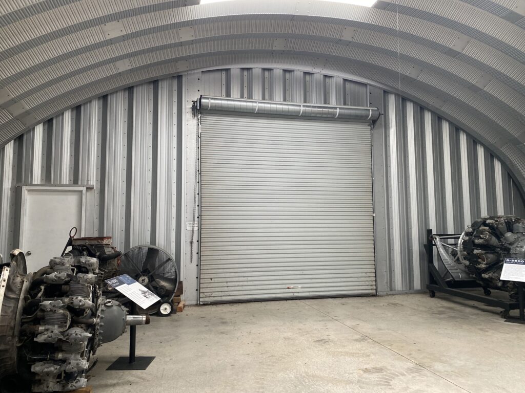 Inside of Quonset hut, metal endwall, rolling door, aircraft engines