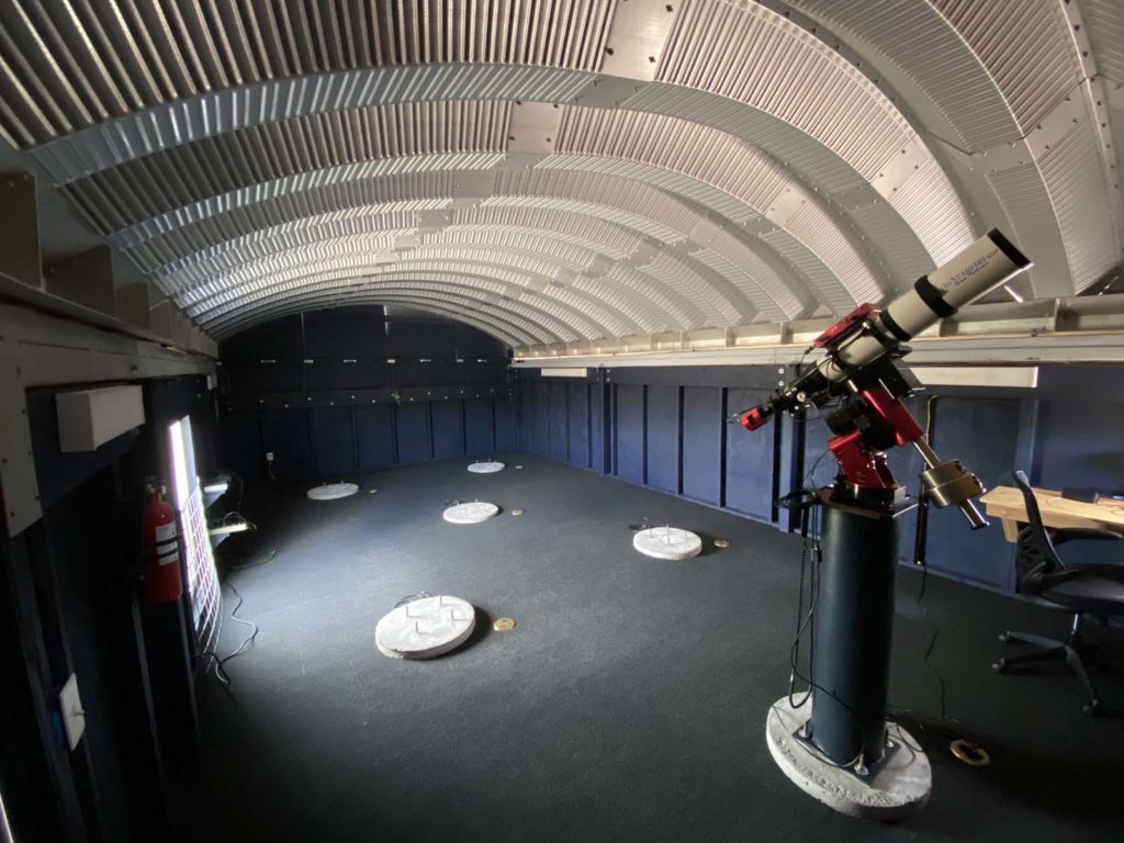 Inside small observatory, steel arched roof, telescope.