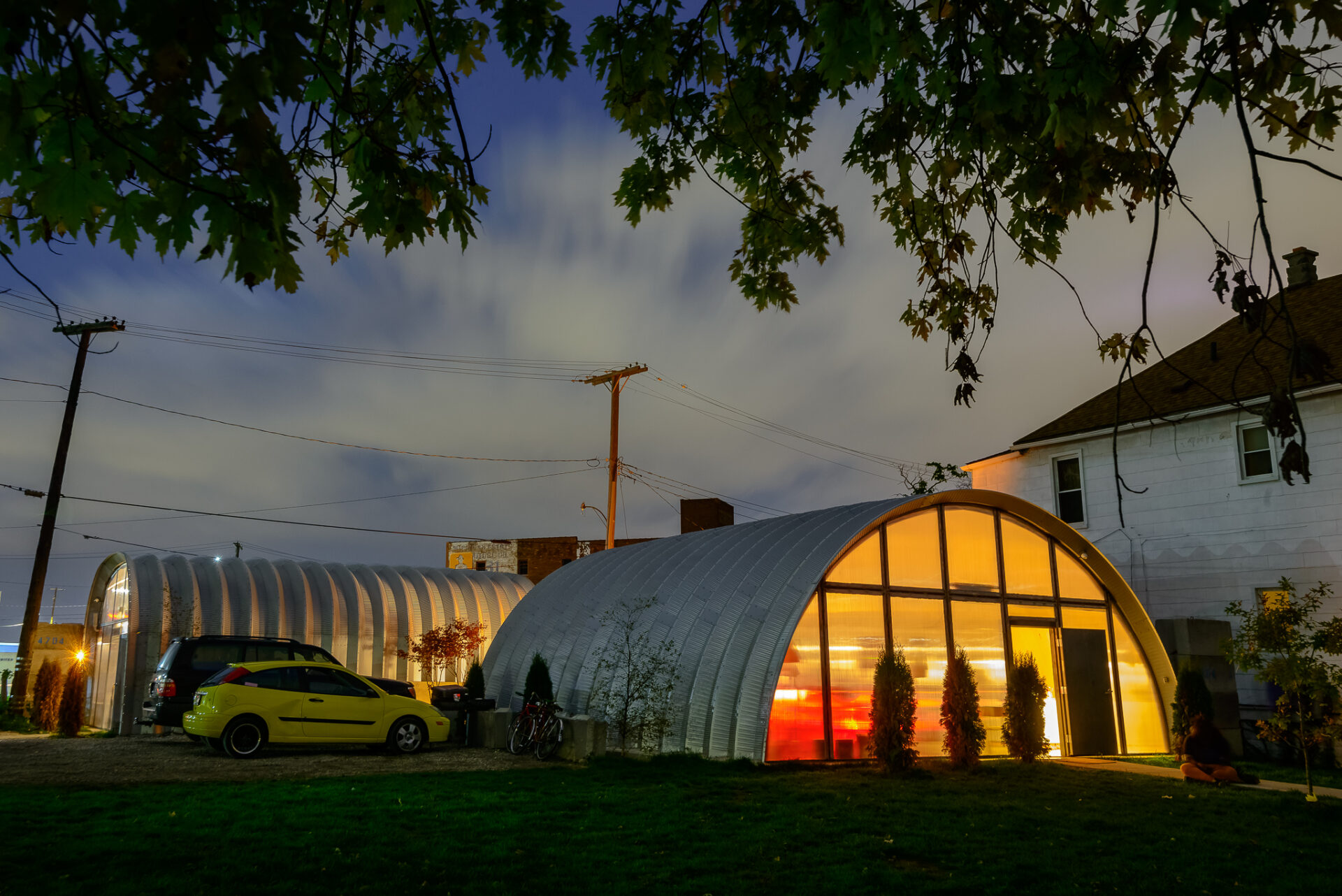exterior of steel building quonset style structures used for many different uses with custom endwalls and windows in the evening