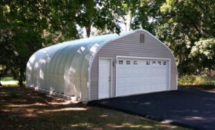A-Model Quonset hut with grey end wall, white garage and man door, and pavement leading up to the building.