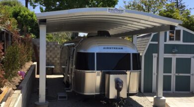 A steel carport with a corrugated roof and an airstream parked underneath