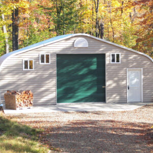 A-Model steel Quonset workshop with custom vinyl front end wall, forest green single garage door, and a white entry door with a pile of firewood out front