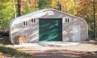 A-Model steel Quonset workshop with custom vinyl front end wall, forest green single garage door, and a white entry door with a pile of firewood out front