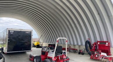 open ended steel quonset hut mounted on stem wall with farm equipment inside
