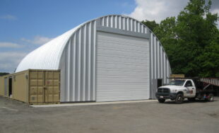 shipping container building with two brown containers, steel roof, steel endwall and large white garage door