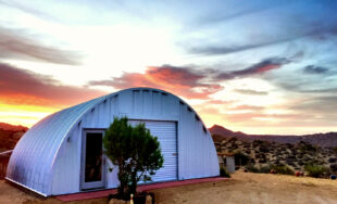 Q-Model Quonset hut with tree in front, bowling pin in front of the tree, and a sunset picture in the background.