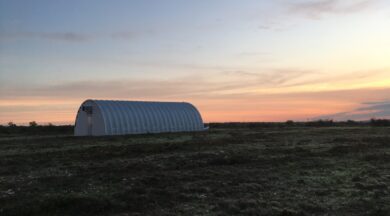 Side view of Q-Model Quonset hut with background of sunset.