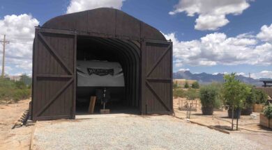 quonset hut with custom brown endwall with sliding doors and rv parked inside