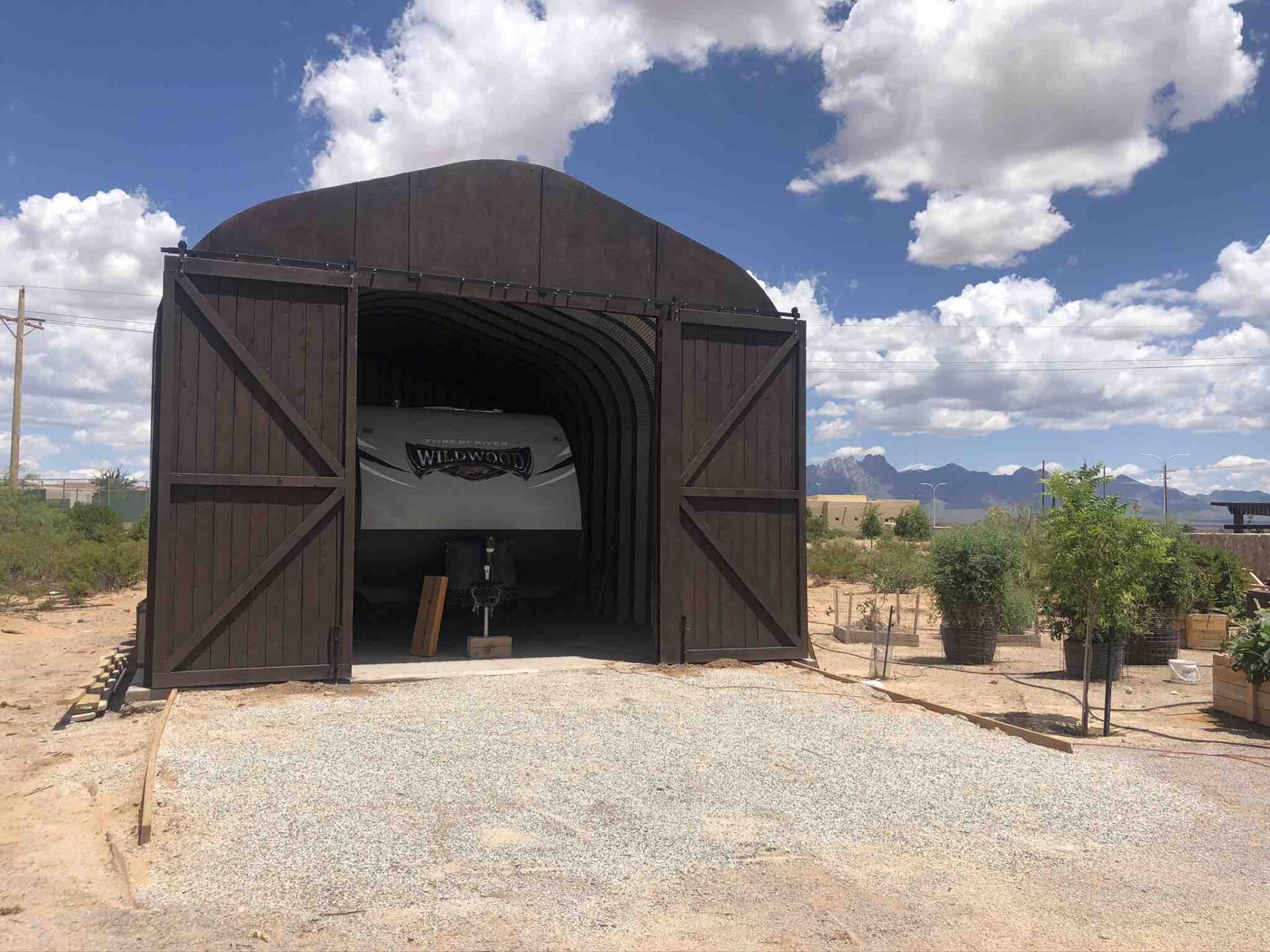 quonset hut with custom brown endwall with sliding doors and rv parked inside