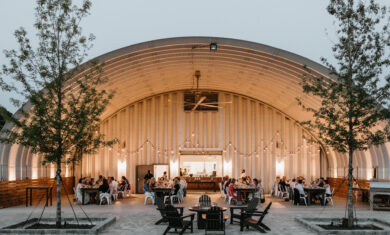large arch S model steel building with steel recessed endwalls to cover large eating area with strong lights up and big ass fan attached to arches and firepit in front