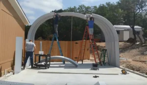 Three people assembling a small Quonset garage on cement foundation.