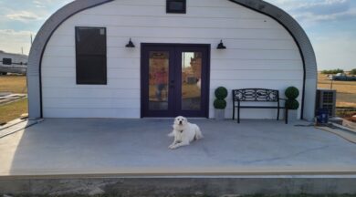 A-frame house with custom white recessed endwall and purple double doors and a white dog laying in front on a concrete slab