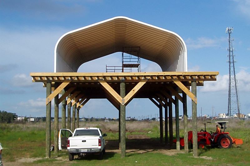 A-Model Quonset hut over white truck and red tractor