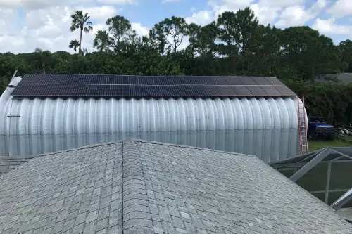 A-model metal building, solar panels on roof, orange ladder leaning up against the side