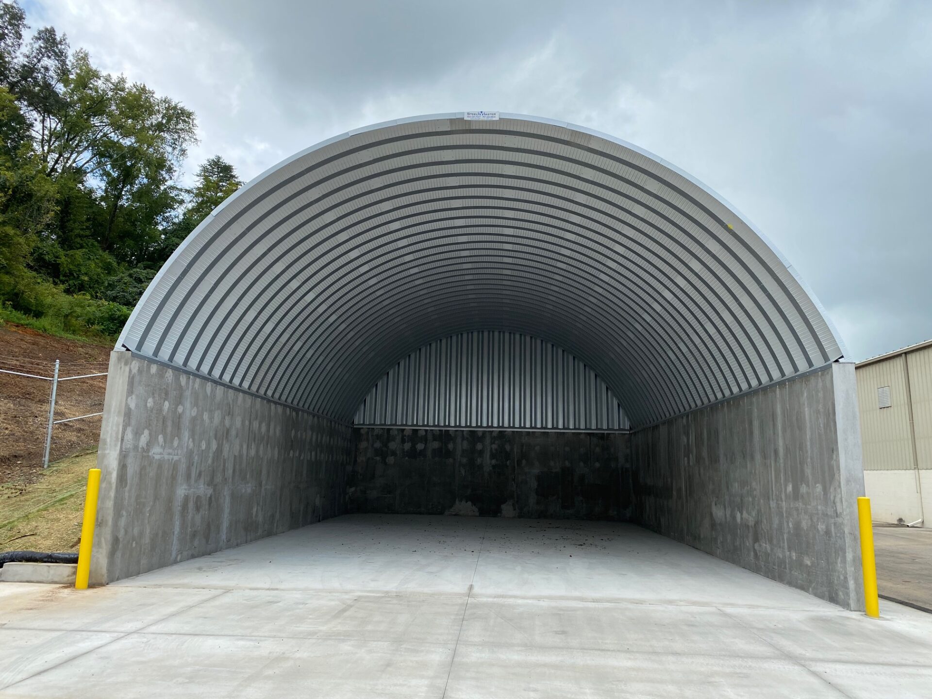 arch steel roof mounted on concrete walls and solid back endwall empty inside
