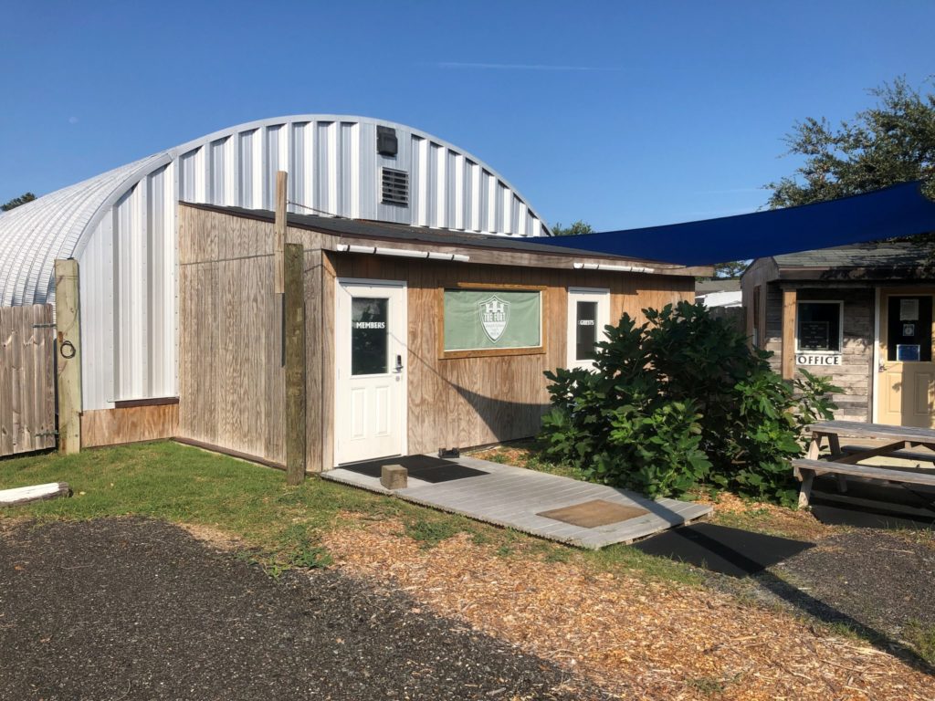 Quonset hut gym with steel endwall attached to a smaller wooden building.