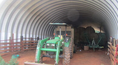 open ended quonset hut interior with john deere tractor and hay bales inside