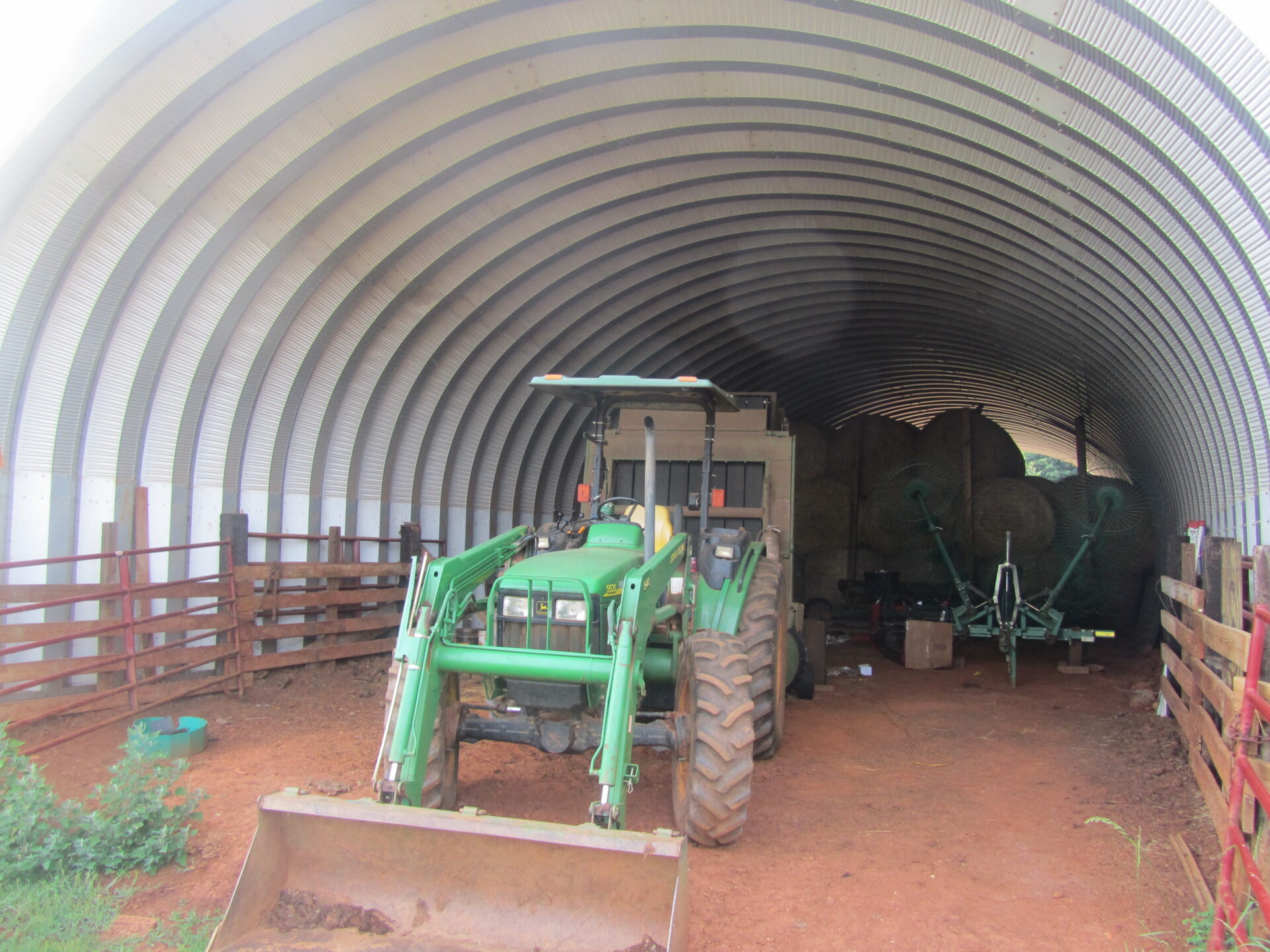 open ended quonset hut interior with john deere tractor and hay bales inside