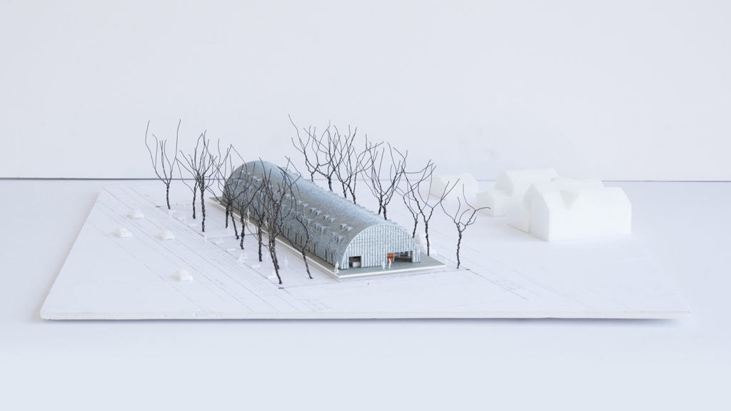3-D model of a steel Quonset hut lined with trees, steel endwall with two open entrances, windows and doors along the sides.