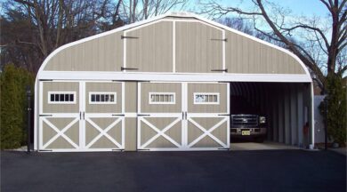 A-Model Quonset hut with two doors for a garage, doors bordered in white, and a black truck in the right garage door.