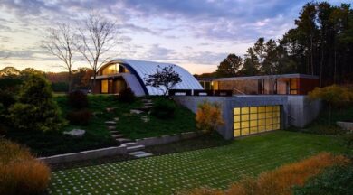 Q model steel arch roof system used for a luxury home in NY with glass garage door and professional landscaping around the home