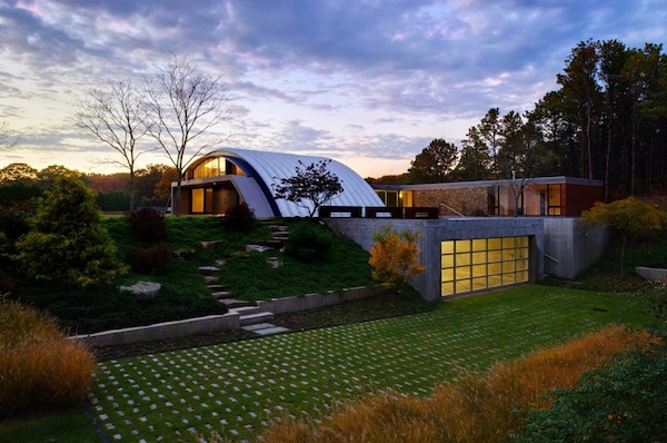 Q model steel arch roof system used for a luxury home in NY with glass garage door and professional landscaping around the home