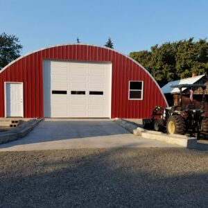 q model steel hay storage building with custom red front endwall and tractor outside