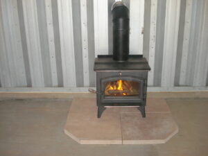 wood stove with fire burning in steel quonset hut