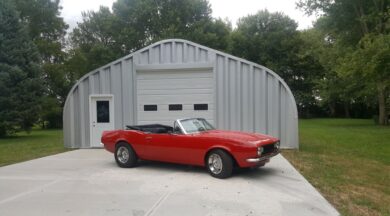 A-Model Quonset hut with garage door, man door, and vintage Mustang in front.