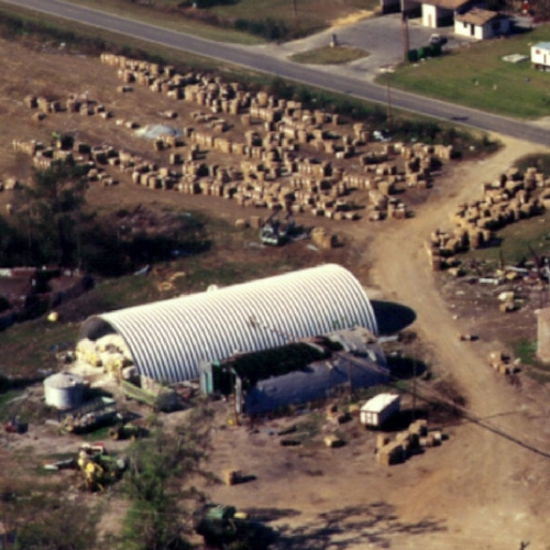 aerial view of large quonset hut on farm surrounded by tornado damage