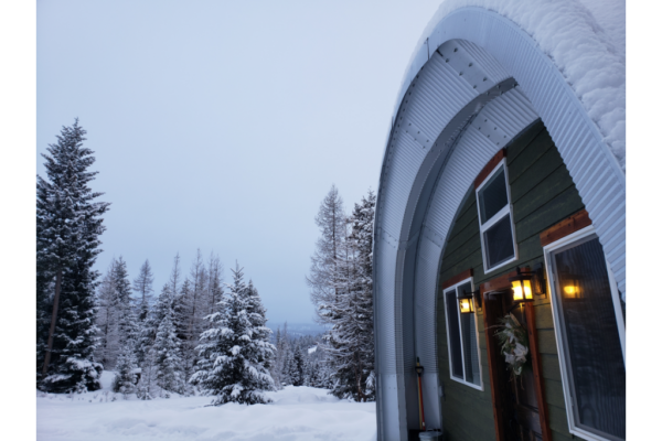 Quonset structure with recessed green endwall covered and surrounded by snow