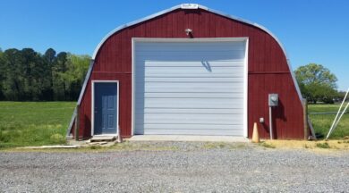 steel quonset hut with custom red endwall, white garage door and blue entry door