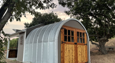 side view of steel S model storage shed with custom front grey endwall with beautiful wood and glass double walk through doors