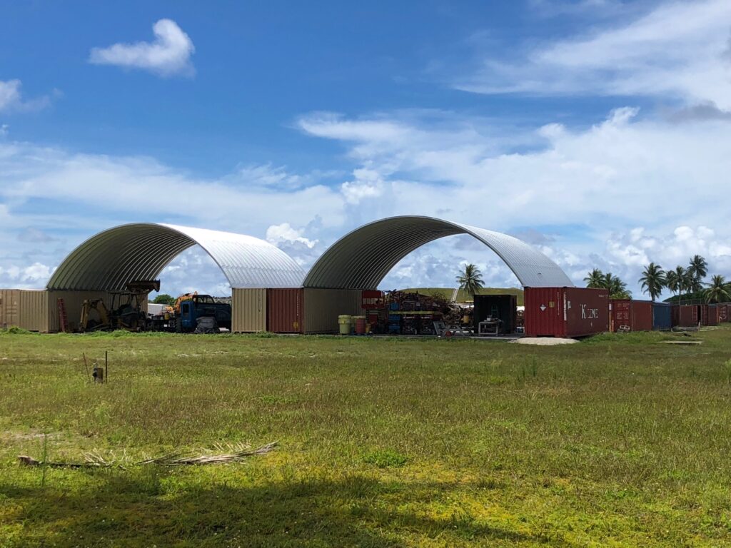 two structures with steel arch roofs mounted on shipping containers
