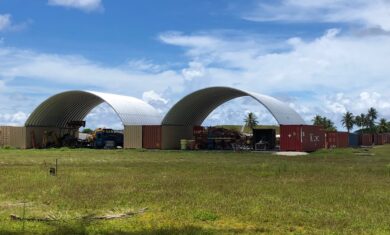 two structures with steel arch roofs mounted on shipping containers