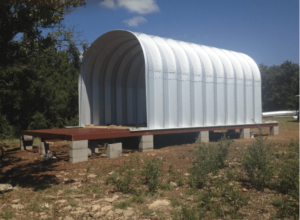 Shell of S-model Quonset casita on raised wooden platform.