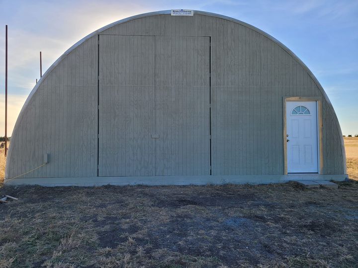 Q-model RV Quonset shed with custom endwall, white entrance door with wood trimming