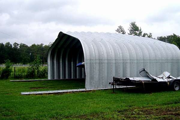 Side view of A-Model Quonset hut with trailer on the outside