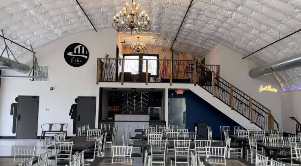 wedding venue inside quonset hut, insulation on ceiling, upper level with staircase, chairs, chandeliers