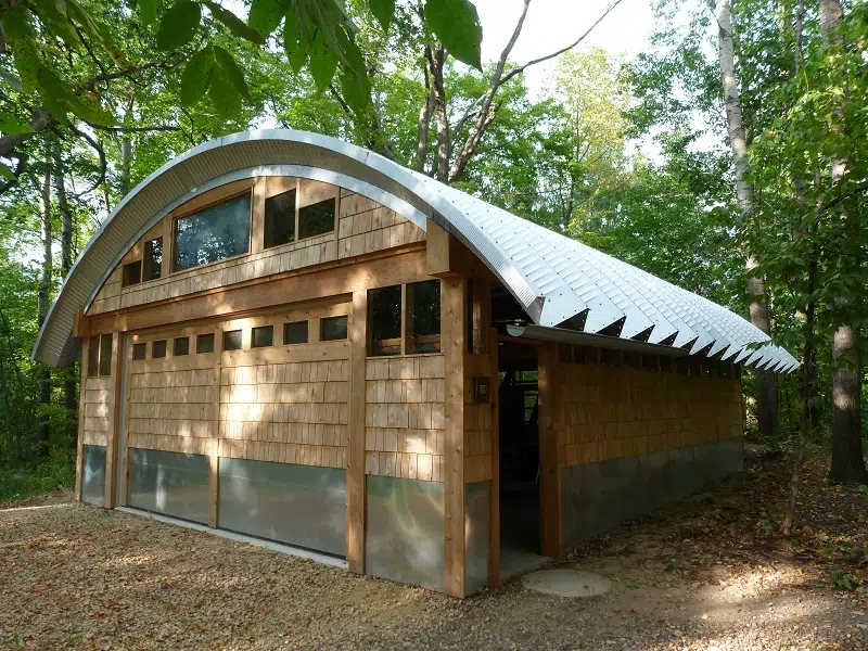 A steel roofing system on top of a custom wood garage with a sliding door in front and an entry door on the side