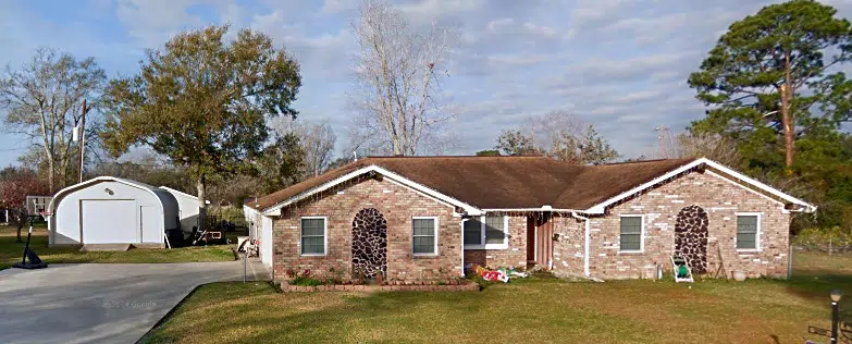 brick home with quonset hut with white endwall at the end of the driveway